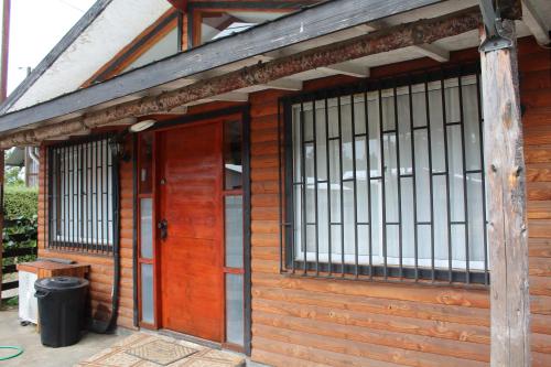 a wooden building with two doors and a trash can at Casa con 3 dormitorios en Licanray, Villarrica in Licán Ray