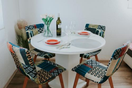 una mesa blanca con sillas y una botella de vino en Kuća za odmor ''FURLAN'' en Gospić
