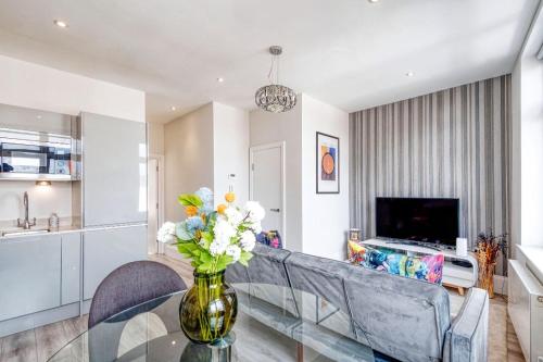 a living room with a vase of flowers on a glass table at Elegant 1 bed apartment- Hampstead Village in London