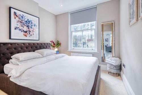 a bedroom with a large white bed and a window at Elegant 1 bed apartment- Hampstead Village in London