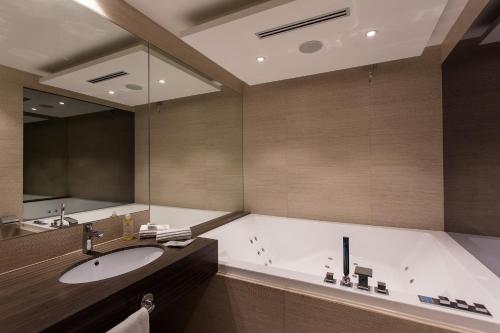 a bathroom with a tub and a sink and a mirror at Diamante MHotel in Collegno