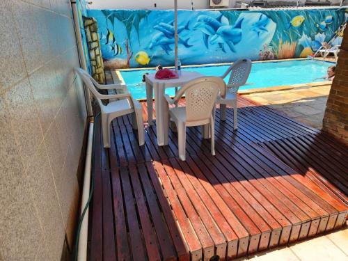 a deck with a table and chairs and a swimming pool at Pousada Jasmine in João Pessoa