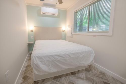 Dormitorio blanco con cama y ventana en Sun Outdoors Cape May, en Cape May