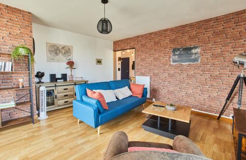 - un salon avec un canapé bleu et un mur en briques dans l'établissement Appartement avec belle vue dégagée du 11e étage, à Brest