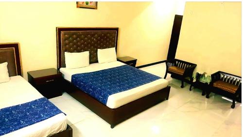 a bedroom with two beds and two chairs in it at Hotel Sky Inn Gulsan in Karachi