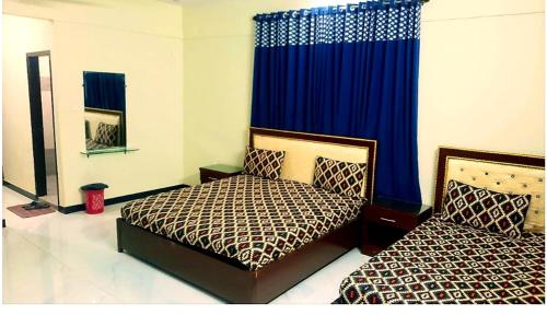 a bedroom with two beds and a blue curtain at Hotel Sky Inn Gulsan in Karachi