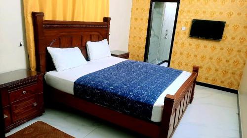 a bedroom with a large bed with a blue blanket at Hotel Sky Inn Gulsan in Karachi