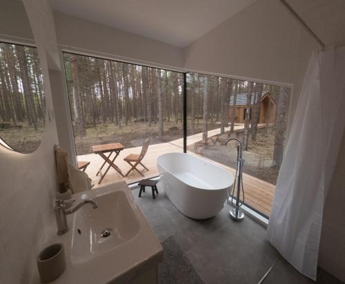 a bathroom with a tub and a view of a deck at WUUD Pädaste in Simisti