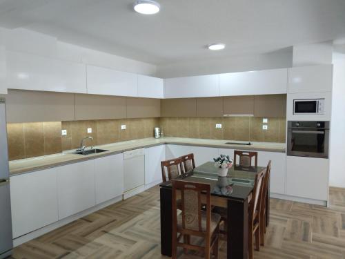 a kitchen with white cabinets and a table with chairs at Z&G Apartment in Bitola