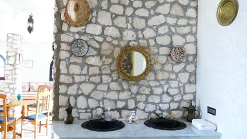 a stone wall with two sinks and a mirror at Villa shahinaz in Essaouira city in Essaouira