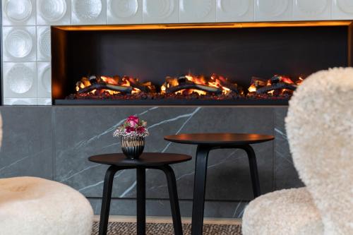 a fireplace with two tables and two chairs at Wellness & Genuss Resort - Engel Obertal in Baiersbronn
