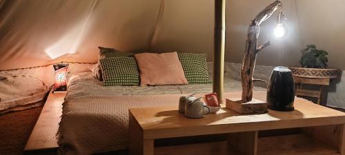 um quarto com uma cama e uma mesa com um candeeiro em Évasion en pleine nature, Tipi insolite à proximité du Pont du Gard ! em Vers Pont du Gard