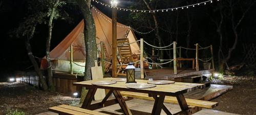 - une table de pique-nique avec une lampe et une tente la nuit dans l'établissement Évasion en pleine nature, Tipi insolite à proximité du Pont du Gard !, à Vers-Pont-du-Gard