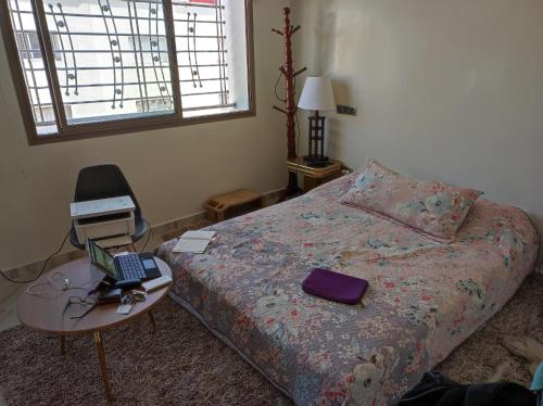 VILLA MALLAK SABIRINE في Nouaceur: غرفة نوم مع سرير مع لاب توب وطاولة