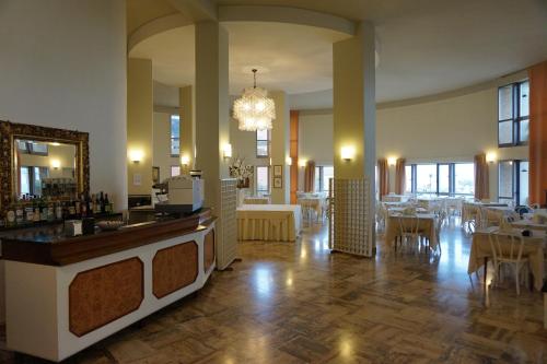 Habitación grande con un restaurante con mesas y una lámpara de araña. en Hotel Palace, en Senigallia