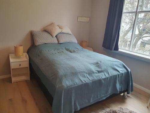 a bedroom with a bed with a blue comforter and a window at Cosy apartment in the old west Reykjavik center in Reykjavík