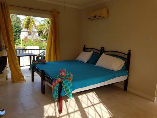 Schlafzimmer mit einem Bett mit blauer Bettwäsche und einem Fenster in der Unterkunft STUDIO Apt Bright comfy with pool on South Coast in Bridgetown