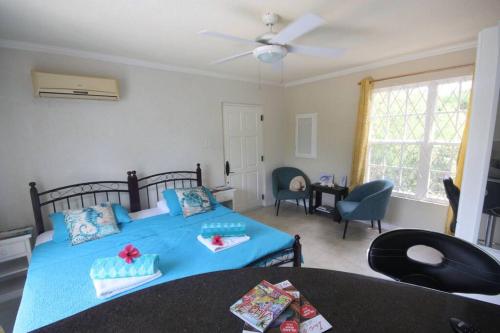 ein Schlafzimmer mit einem blauen Bett und ein Wohnzimmer in der Unterkunft STUDIO Apt Bright comfy with pool on South Coast in Bridgetown
