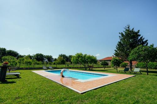 a swimming pool with a dolphin in the grass at Os Migueliños in Catoira