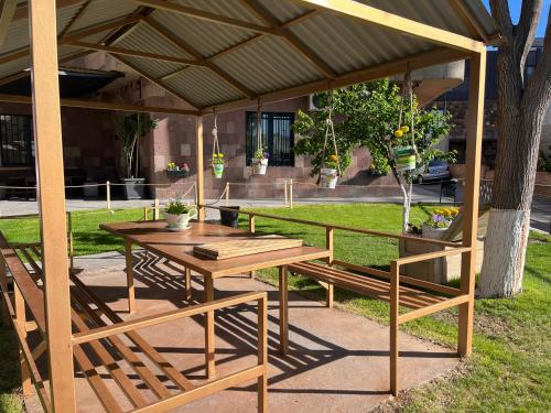 een houten picknicktafel en bank onder een prieel bij Street51 in Jerevan