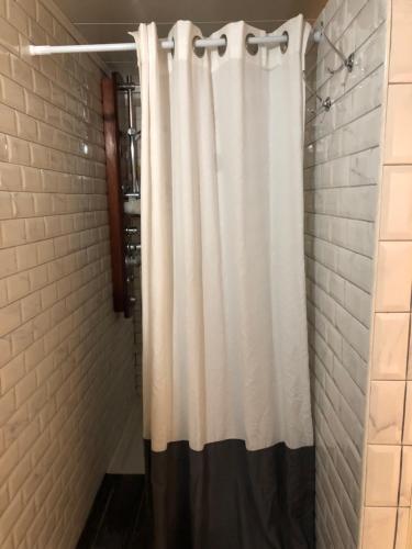 a shower with a white shower curtain in a bathroom at Chambre dans maison cosy in Marquillies