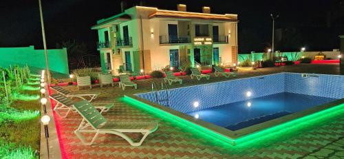 - une piscine en face d'une maison la nuit dans l'établissement Sierra Hotel Tbilisi, à Tbilissi