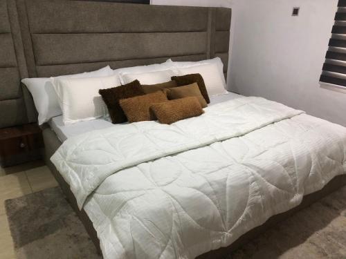 een wit bed met kussens in een slaapkamer bij Exquisite and Cozy 3-bedroom Apt with hot-tub and WiFi in Agege