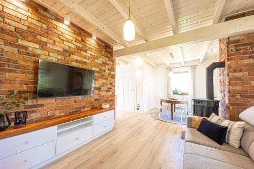 a living room with a brick wall with a flat screen tv at Uroczysko Lubajny in Idzbark
