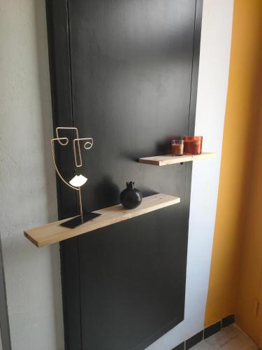 a shelf on a black wall with a vase on it at "Les Chacobins" - appart'étape avec Garage Vélos in La Réole