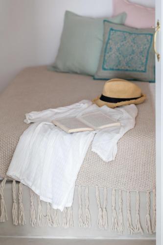 a bed with a white shirt and a book on it at Cleo's Dream Villa in Oia