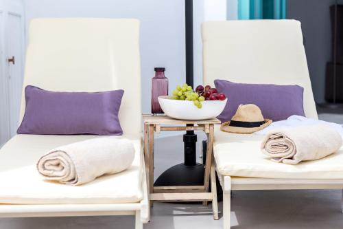 2 weiße Stühle mit einem Tisch und einer Obstschale in der Unterkunft Cleo's Dream Villa in Oia