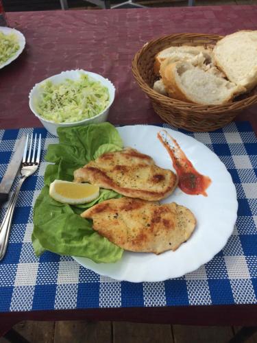 a plate of food with chicken and lettuce and bread at Small Cabin on river Jabukov cvet in Banatski Brestovac