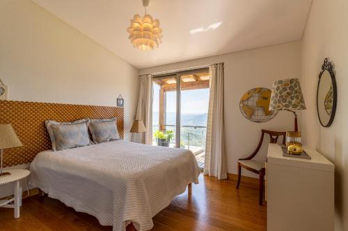 a bedroom with a bed and a large window at Quintinha do Miradouro - casa completa com 4 quartos! in Mesão Frio
