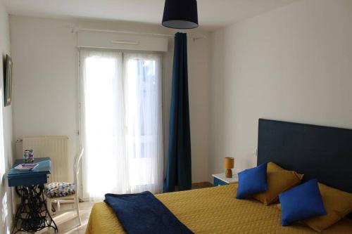 - une chambre avec un lit doté d'oreillers bleus et d'une fenêtre dans l'établissement Maison sur les hauteurs de Carcassonne, à Carcassonne