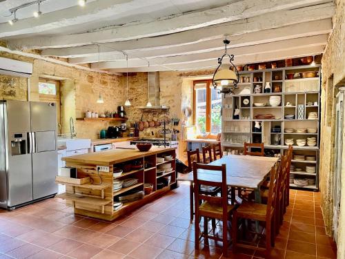 eine Küche mit einem Tisch und einem Kühlschrank aus Edelstahl in der Unterkunft Esparoutis in Saint-Cybranet