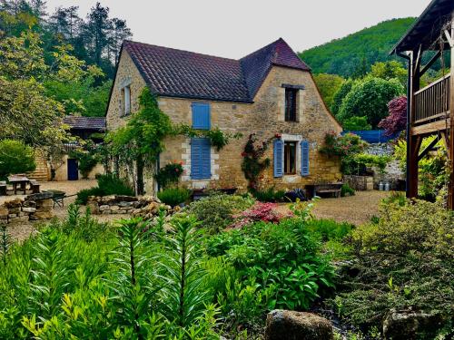 an old stone house with blue shutters in a garden at Esparoutis in Saint-Cybranet