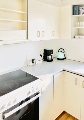 a white kitchen with white cabinets and a tea kettle at Scandinavian Apartment Hotel - Tobaksgården - 2 room apartment in Horsens