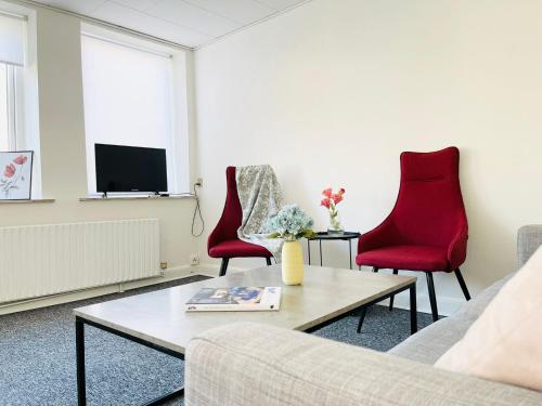 uma sala de estar com um sofá e duas cadeiras vermelhas em Scandinavian Apartment Hotel - Tobaksgården - 2 room apartment em Horsens