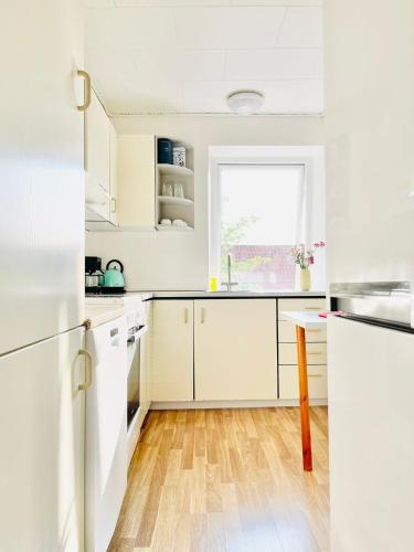 a white kitchen with white cabinets and a window at Scandinavian Apartment Hotel - Tobaksgården - 2 room apartment in Horsens