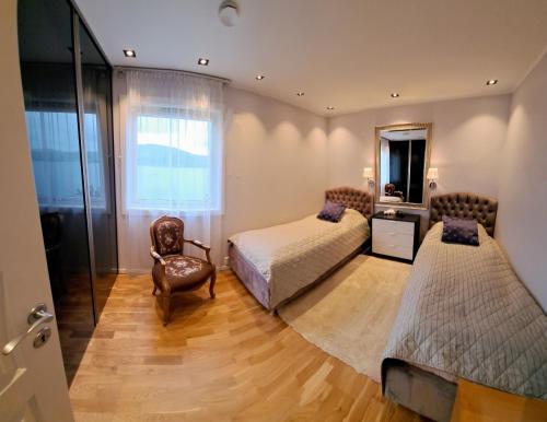 a bedroom with two beds and a chair and a mirror at Bergen Sunrise Terrace Apartment in Bergen
