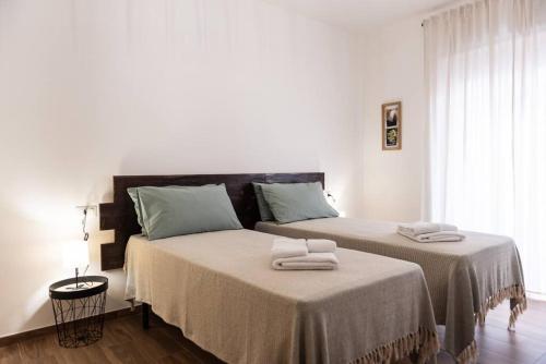 - une chambre blanche avec 2 lits et des serviettes dans l'établissement Da Zietta casa dal sapore tipico, à Castellana Grotte