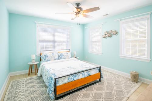 ein blaues Schlafzimmer mit einem Bett und einem Deckenventilator in der Unterkunft The Starfish Cove in Carolina Beach