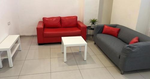 una sala de estar con 2 sofás y una silla roja en Downtown spacious Apartment, en Haifa