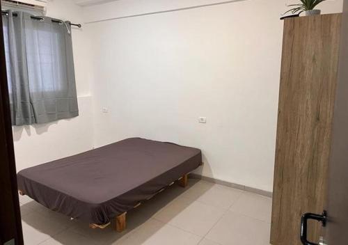 1 dormitorio con 1 cama en una pared blanca en Downtown spacious Apartment, en Haifa