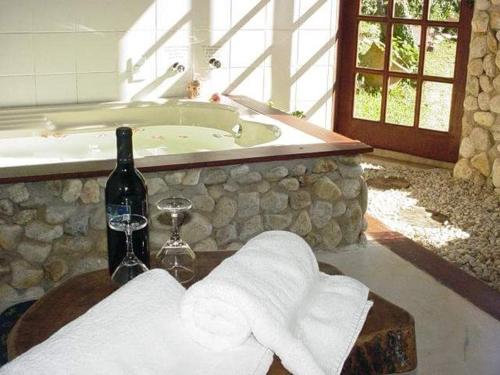 a bathroom with a tub and a bottle of wine and towels at Pousada Lua e Sol in Santo Antônio do Pinhal