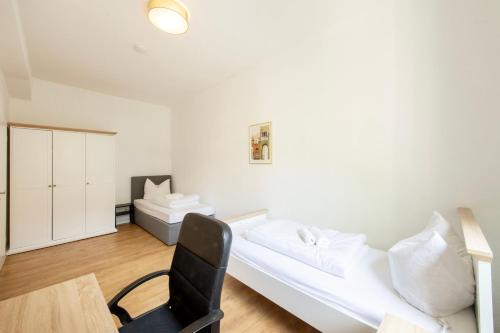 a bedroom with a white bed and a black chair at Stay and Work Apartment - 8 single beds - central in Gronau