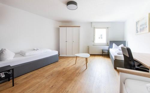 a white bedroom with a bed and a table at Stay and Work Apartment - 8 single beds - central in Gronau