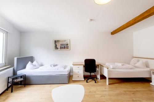 a room with two beds and a desk and a chair at Stay and Work Apartment - 8 single beds - central in Gronau