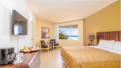a hotel room with a bed and a television at Puerto Nuevo Baja Hotel & Villas in Rosarito