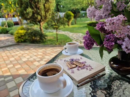 twee kopjes koffie op een glazen tafel met bloemen bij Villa ZENKO in Lviv